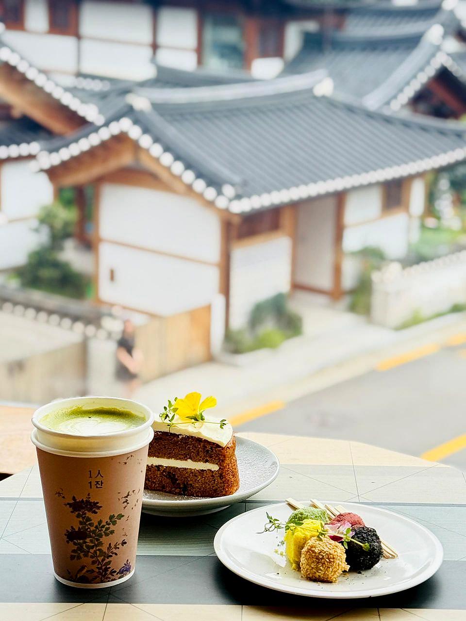Drinks, cake and colorful small treats with hanok roofs beyond