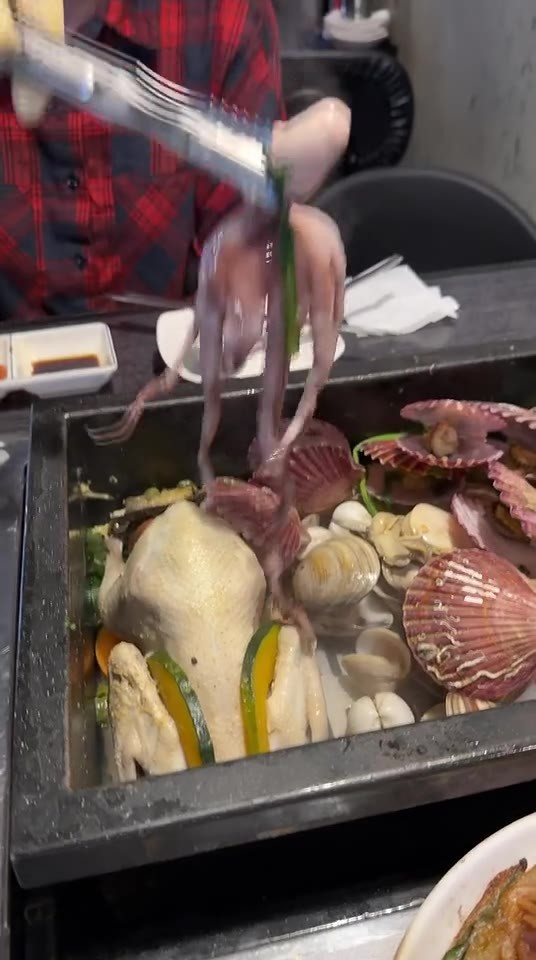 工作人员处理海鲜锅中的章鱼